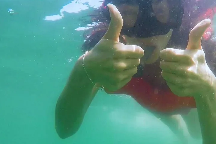 Person underwater giving two thumbs up while wearing a snorkel mask